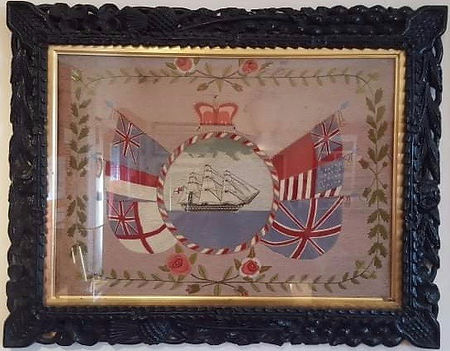Embroidery of sailing ship on the sea framed by circular border of flags and flowers